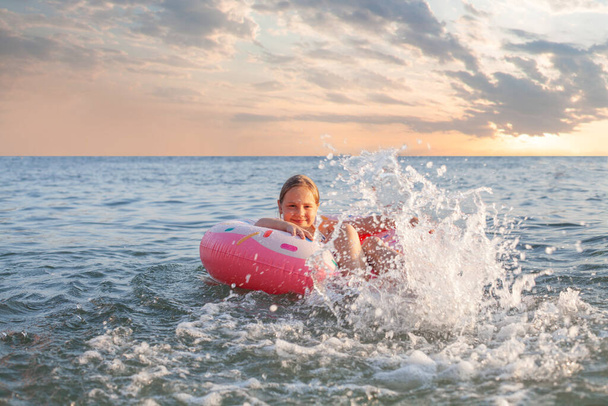 Szczęśliwy dzieciak bawiący się na morzu. Radosna dziewczynka na nadmuchiwanym pierścionku. Styl życia podróży, pływanie i wakacje na tropikalnej koncepcji wyspy - Zdjęcie, obraz