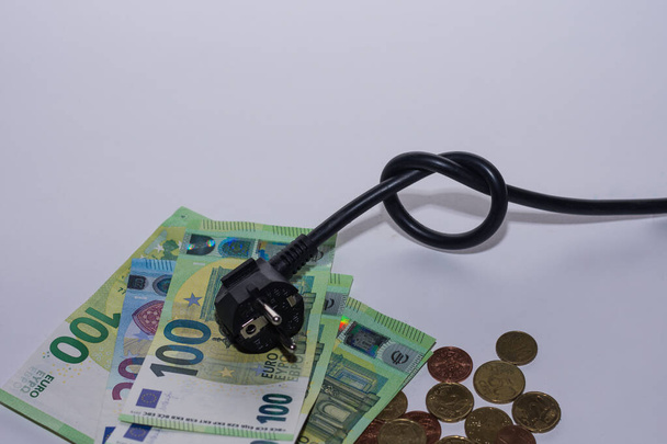Energiepreise steigen und Energieverbrauch Stromkabel mit Knoten und Geld mit grauem Hintergrund Unterseite Ansicht - Foto, Bild