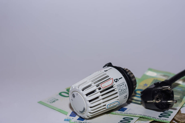 Wzrost cen energii i zużycie energii regulator termostatyczny ogrzewanie i wtyczka elektryczna oraz 100 euro rachunki z szarym tle prawy widok dolny - Zdjęcie, obraz