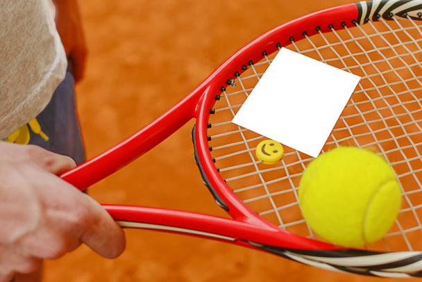 Male player holding tennis ball and racket on tennis court with blank white paper - Photo, Image
