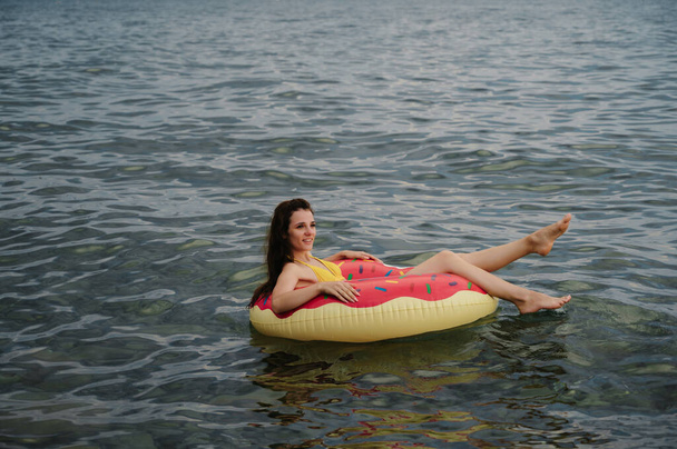 esbelta chica nada en un círculo inflable en el mar en verano - Foto, imagen