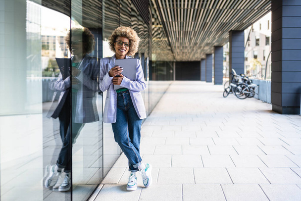 Retrato de jovem líder mulher afro-americana a nova empresa moderna criativa de pé na área de escritório ao ar livre segurando laptop - Foto, Imagem