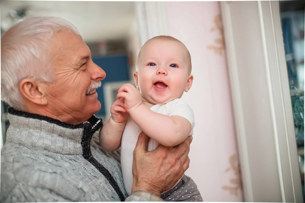 Egy idős férfi tartja az unokáját. Boldog nagyapa egy kislánnyal a karjában. Az elszigeteltség megszűnése és az otthoni rokonok családi légkörben való találkozása az ünnepek alatt. - Fotó, kép