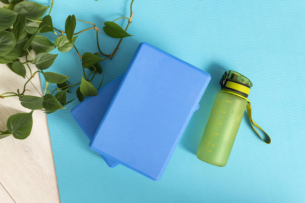 Yoga bricks and water bottle on the yoga mat. Instruments for gymnastics and stretching - Photo, Image