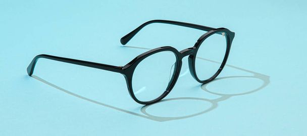 Business black glasses on blue background. Fashion office glasses reading in summer concept for promo banner sale and shopping - Valokuva, kuva