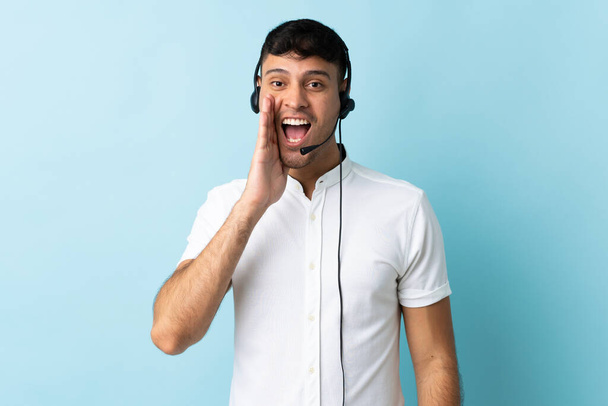 Hombre colombiano telemarketer trabajando con un auricular sobre fondo aislado con expresión facial sorpresa y conmocionada - Foto, Imagen
