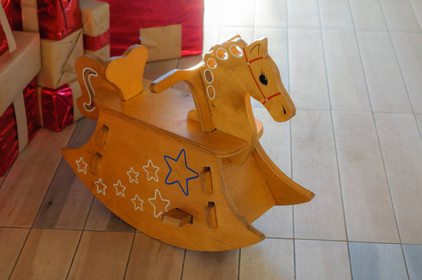 ξύλινο παιδικό κουνιστό άλογο, Χριστουγεννιάτικη σκηνή, δώρα κάτω από το δέντρο της Πρωτοχρονιάς, μαλακό φώς - Φωτογραφία, εικόνα