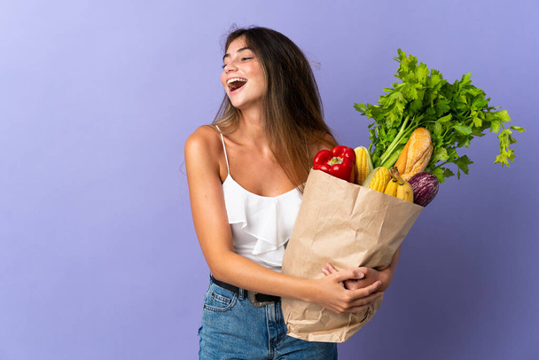 Young woman holding a grocery shopping bag laughing in lateral position - Photo, Image