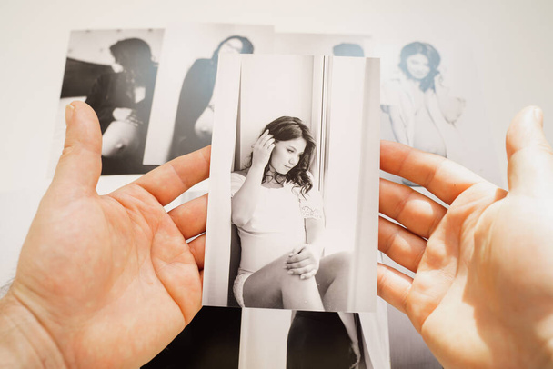 Mens hands hold pictures of a beautiful pregnant woman.  - Foto, imagen