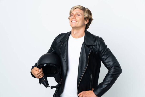 English man holding a motorcycle helmet posing with arms at hip and smiling - Фото, изображение