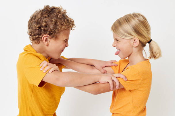 two joyful children in yellow t-shirts standing side by side childhood emotions light background unaltered - Photo, image