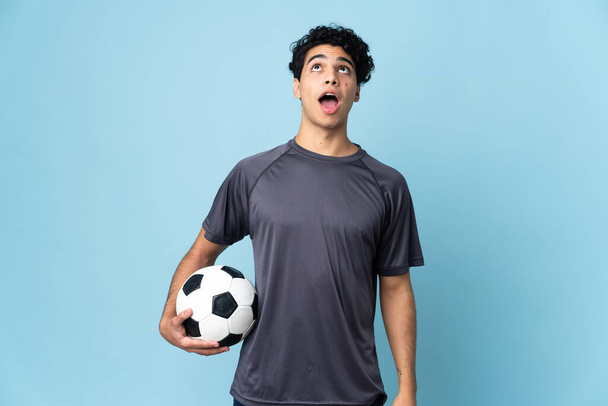 jugador de fútbol venezolano hombre sobre fondo aislado mirando hacia arriba y con expresión sorprendida - Foto, Imagen