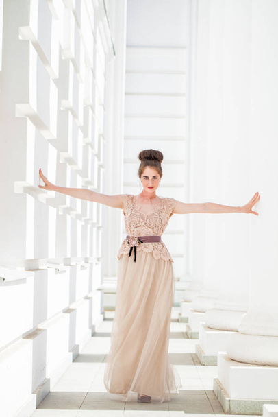 Young beautiful brunette in a luxurious beige dress posing on the street - Fotografie, Obrázek