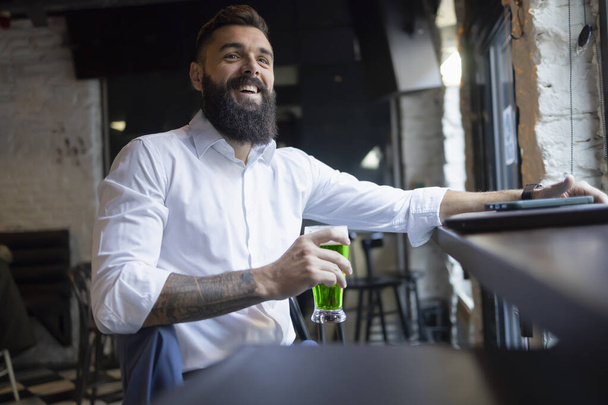Mężczyzna siedzący w pubie ze szklanką zielonego piwa na dzień św. Patryka. - Zdjęcie, obraz