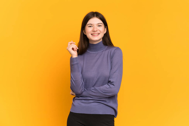 Young Ukrainian girl isolated on yellow background laughing - Foto, imagen