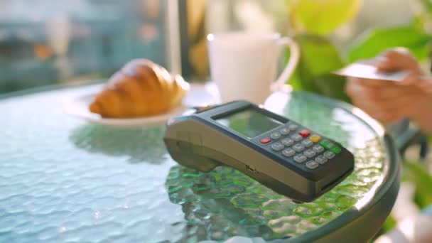 NFCクレジットカード決済。カフェで銀行ターミナルで注文を支払うためにNFC技術と非接触クレジットカードで支払う女性。無線資金取引だ。ワイヤレス決済 - 映像、動画