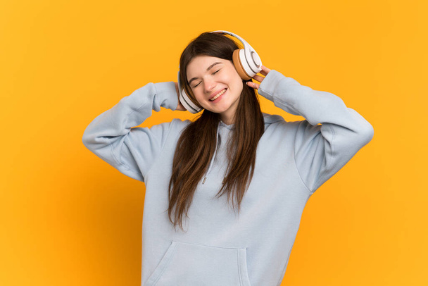 Nuori ukrainalainen tyttö eristetty keltainen tausta kuuntelee musiikkia - Valokuva, kuva