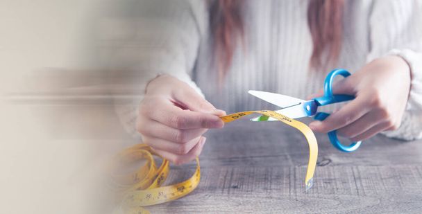 woman cuts measuring tape with scissors - Valokuva, kuva