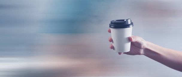 a female hand holds a disposable cup of coffee - Photo, Image