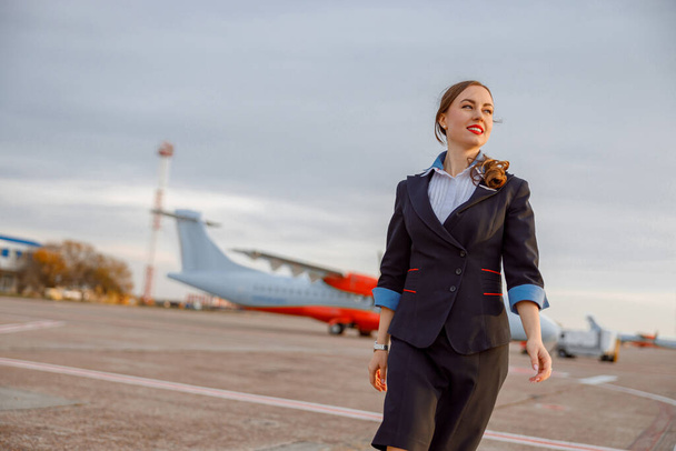 Fröhliche Flugbegleiterin läuft über Flugplatz - Foto, Bild