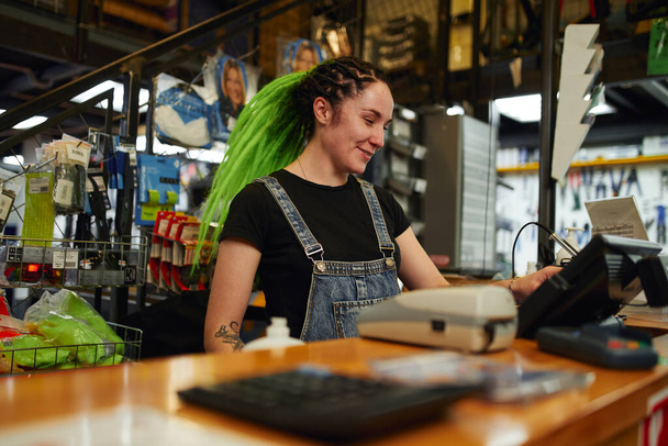 Young woman entering data in cash register in store - Fotoğraf, Görsel