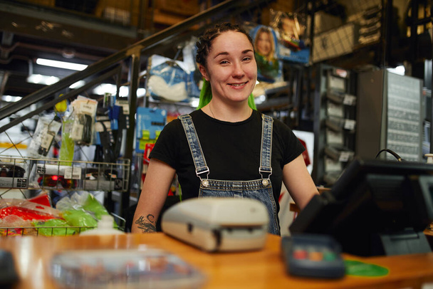 Cheerful female cashier smiling at camera in store - Photo, Image