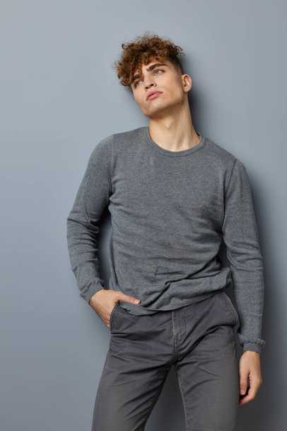 handsome young man in a gray sweatshirt fashion studio isolated background - Zdjęcie, obraz