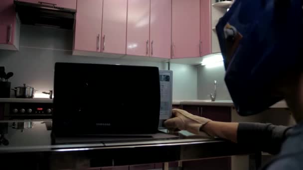 Mężczyzna otwiera musujące zepsuty kuchenka mikrofalowa noszenie maski spawalniczej i rękawice w kuchni - Materiał filmowy, wideo