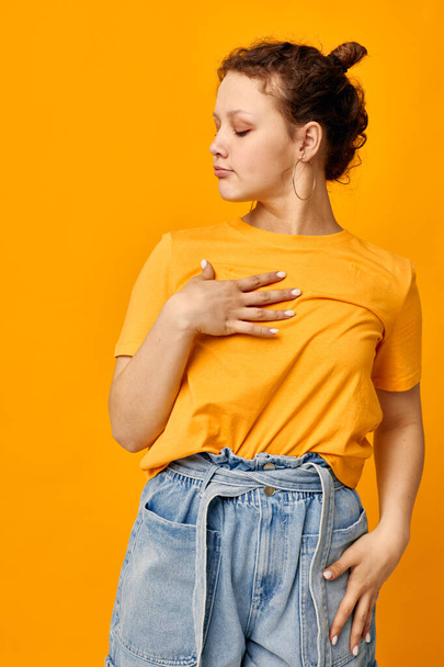 pretty girl gestures with hands grimace emotions yellow background unaltered - Foto, afbeelding