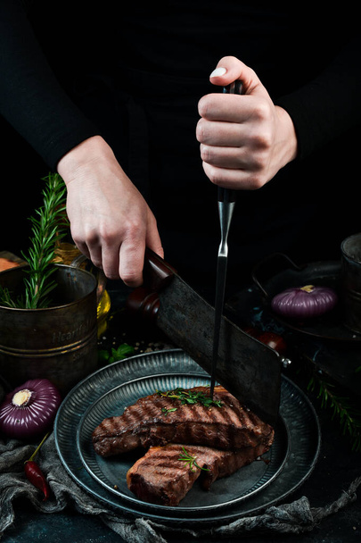 The chef cuts the grill steak. On a black stone background. - Photo, image