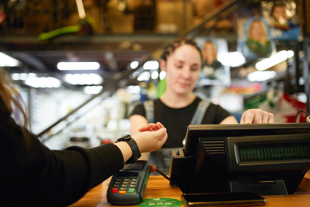 Female customer paying with smart watch via terminal - Foto, immagini
