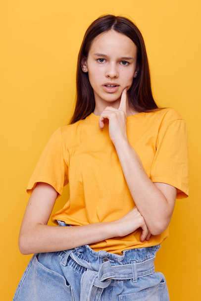 optimistic young woman in a yellow t-shirt emotions summer style yellow background - Foto, afbeelding