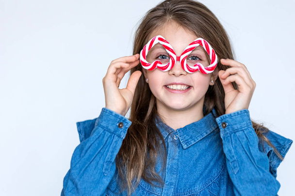 Funny happy girl child in inverted caramel glasses looks at the camera with hearts and smiles. Copy space for text - Foto, Imagen