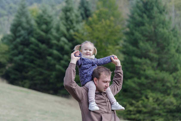 Father and daughter enjoying a piggyback ride at park - Photo, Image
