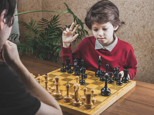 Ojciec i syn spędzają razem czas grając w szachy w domu. - Zdjęcie, obraz