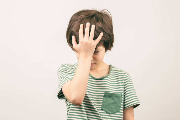 Csalódott kisiskolás fiú, aki kezet emelt a fejére. Arcpálmafa gesztus - Fotó, kép