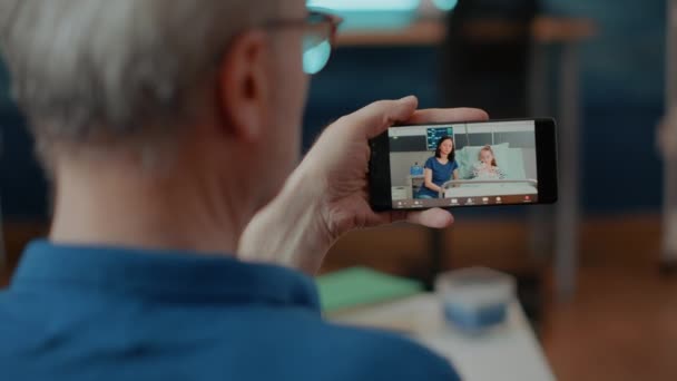 Adulto jubilado usando videollamada en línea en teléfono móvil - Imágenes, Vídeo