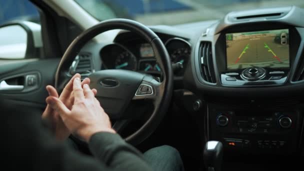 Mies ajaa innovatiivisella automatisoidulla autolla käyttäen autopilottia pysäköintiin parkkipaikalla. Takanäkymä kuljettajan olkapään takaa - Materiaali, video