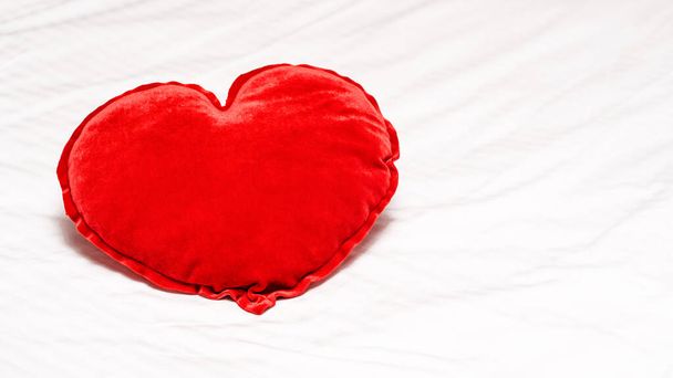 Red hearts shaped pillow on bed in bedroom. Valentine's day couple concept. High quality photo - 写真・画像