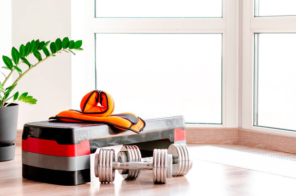 Sports concept. Sport equipment. Set of sports equipment for fitness classes on the floor against the window - Фото, изображение
