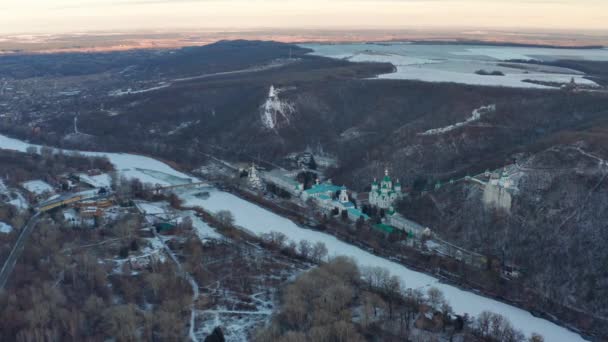 Vuelo de invierno sobre la Santa Dormición Svyatogorsk Lavra. Hay muchas iglesias arriba. Monasterio ortodoxo desde arriba. El río está cubierto de hielo. Paisaje invernal en la nieve. - Imágenes, Vídeo