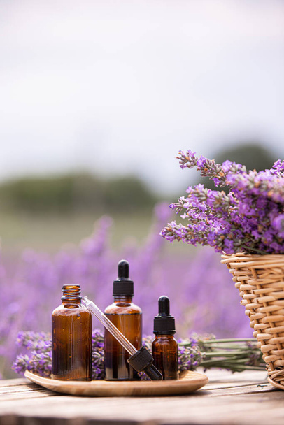 Amber essential lavender oil bottle. Violet lavendar field in Provence. - Photo, Image