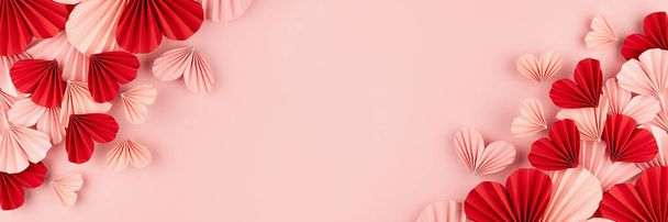 Bright and passion Valentines day banner for website - mix of pink and red paper ribbed hearts flying on soft light pastel pink background as sideways border, frame with copy space, top view. - Foto, imagen