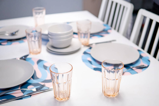 Κενό σερβίτσιο σε μοντέρνο λευκό τραπέζι. Πιάτο, μπολ, ποτήρι και μαχαιροπήρουνα - Φωτογραφία, εικόνα
