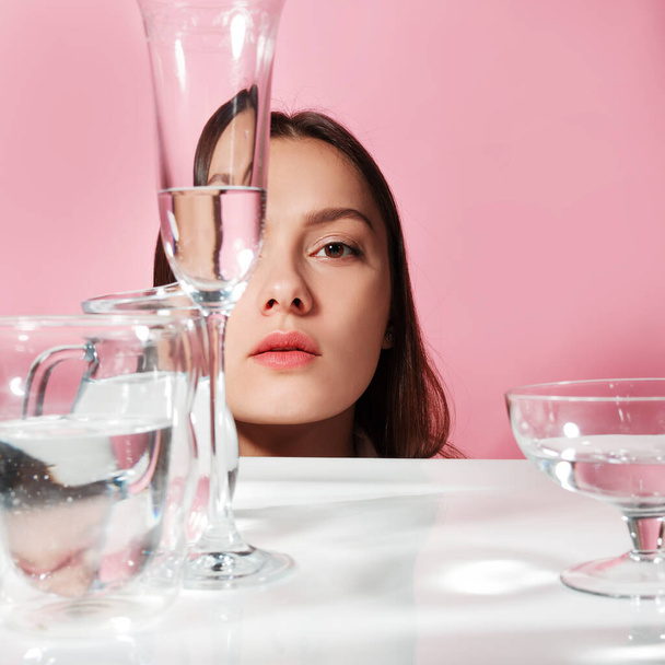 Portrait of a young brunette in refraction through glasses of water - 写真・画像