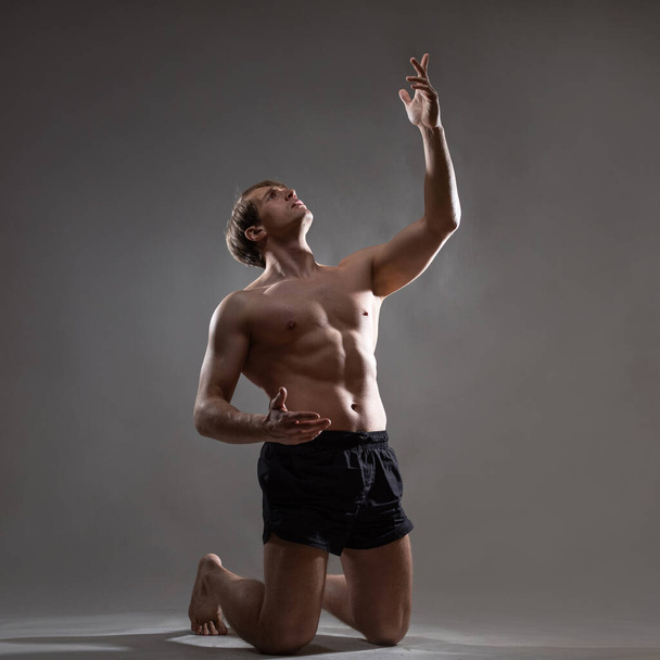 A young muscular man in an expressive pose. Beautiful muscles. - Foto, Bild