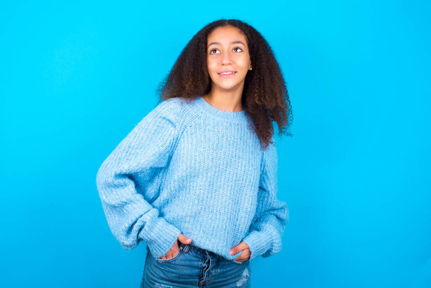 Muotokuva onnistuneen Afrikkalainen amerikkalainen teini tyttö afro hiukset tyyli yllään sininen pusero sinisellä taustalla, hymyillen laajasti itsevarma ilme. Luottamus ja liiketoiminnan käsite. - Valokuva, kuva
