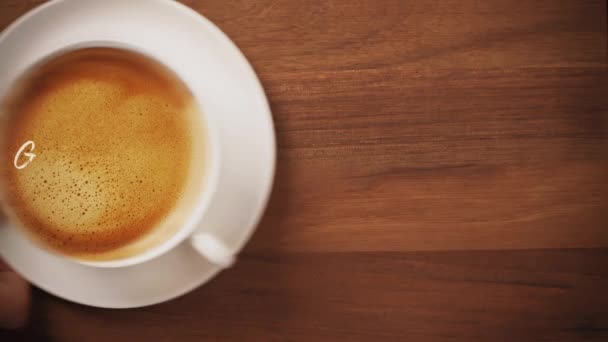 Vista superior de una mano que sirve café con buen arte de latte de texto de la mañana - Imágenes, Vídeo