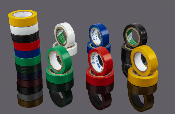 Several coils of colored tape (insulating tape) on black background. Adhesive tape (Electrical tapes) on a black background. View from above - Φωτογραφία, εικόνα
