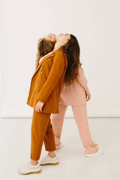 Mujeres jóvenes con estilo en trajes de pastel de pie juntos, concepto de moda - foto de stock - Foto, imagen